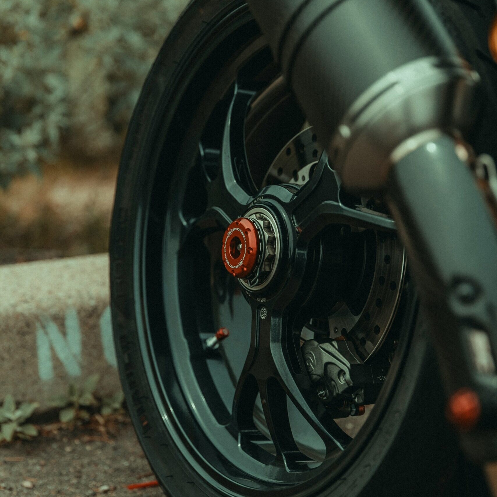 Motorrad Hinterrad mit schwarzer Felge und Sportauspuff als Beispiel für professionelles Felgen richten und Pulverbeschichten